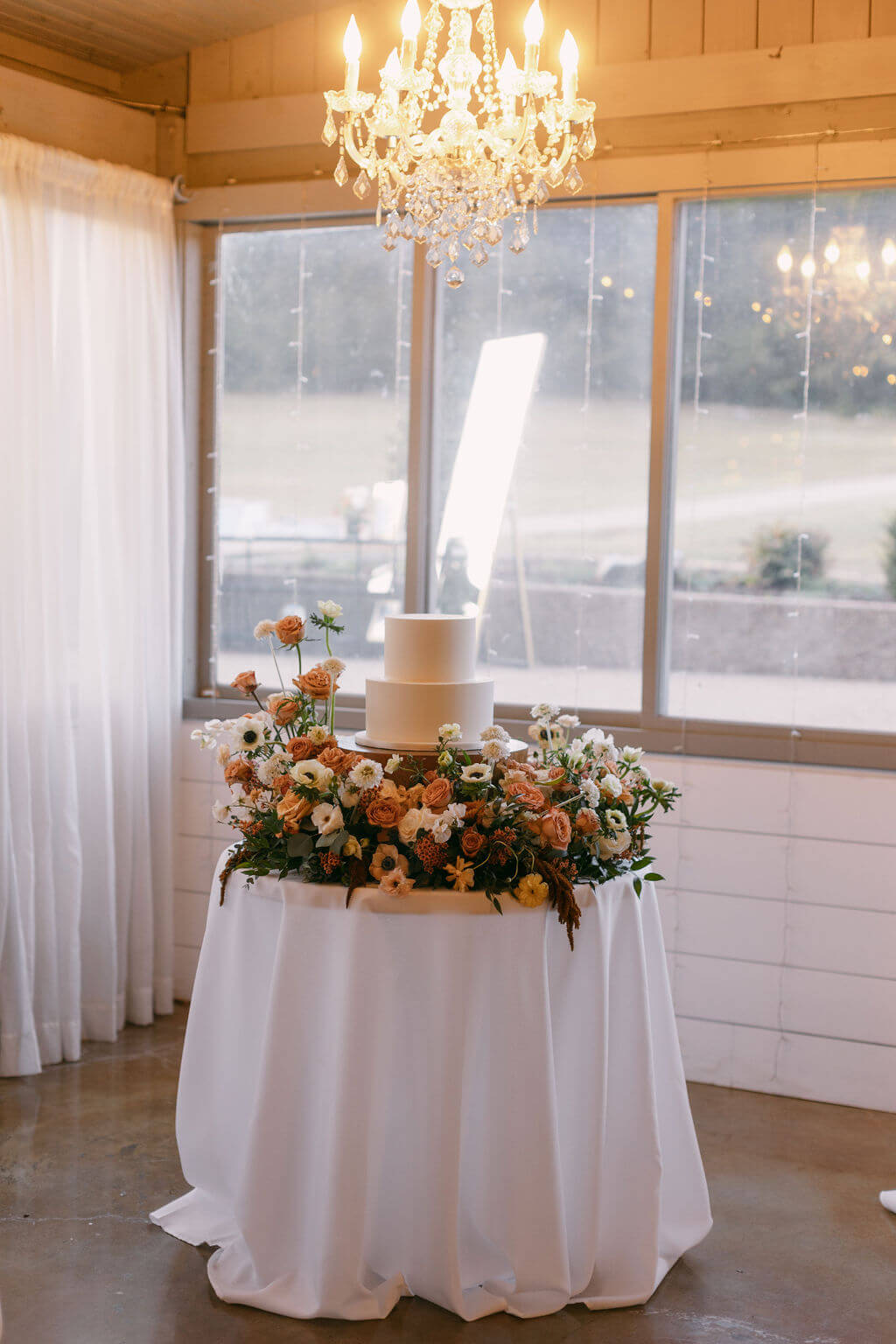 a wedding cake on a white table with flowers surrounding the base of the cake